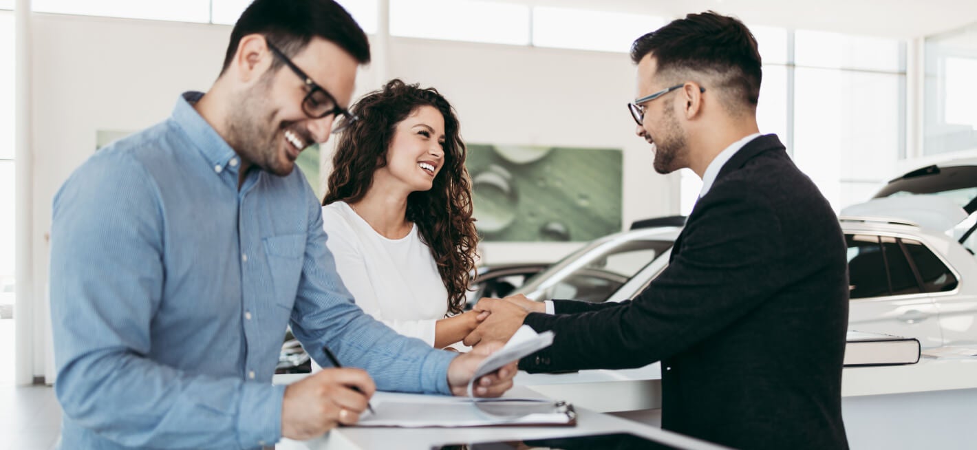 Customers speaking and signing papers with a Kia sales associate